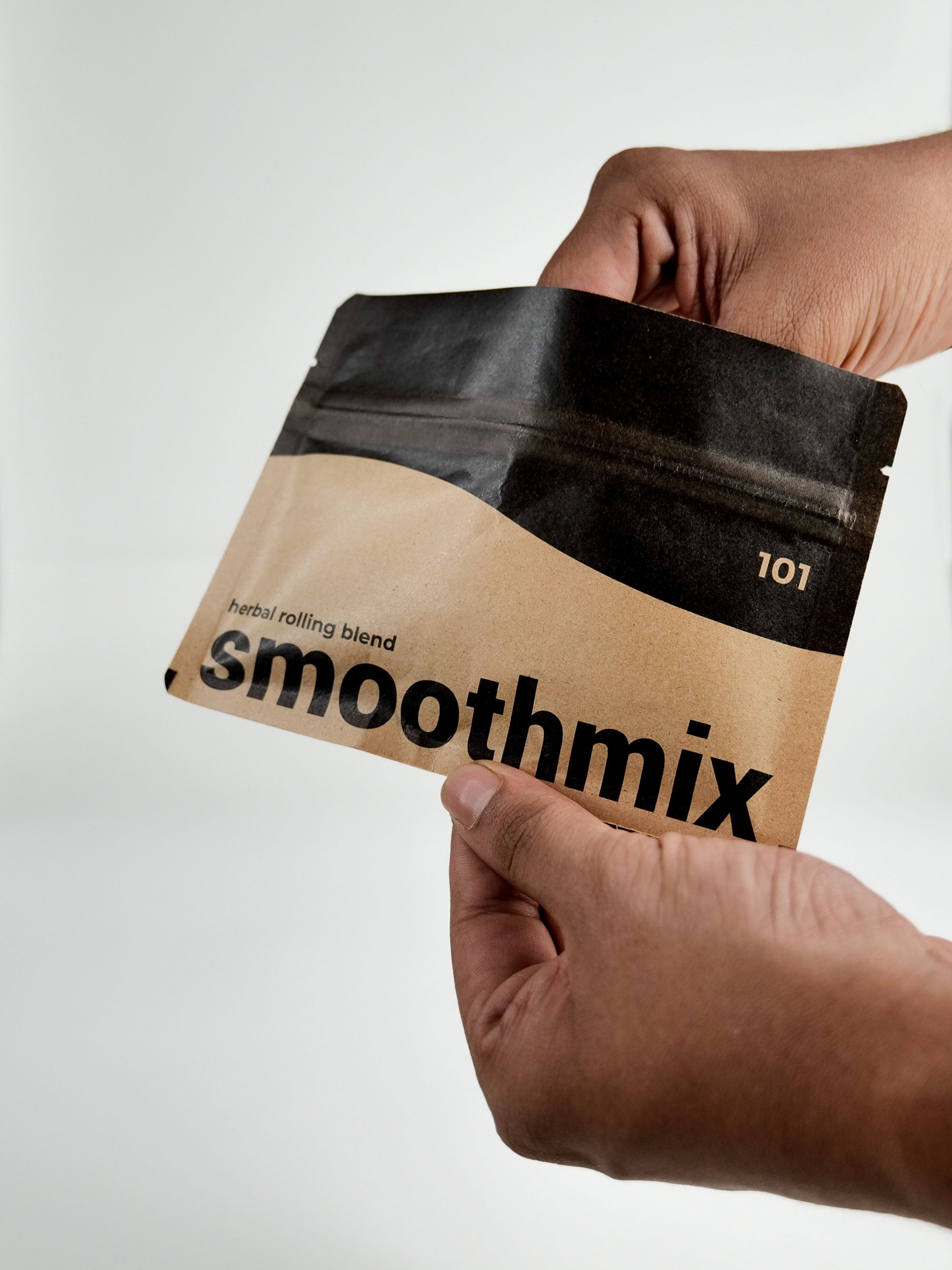 Hand holding a package of Smoothmix 101 herbal blend on a light gray background