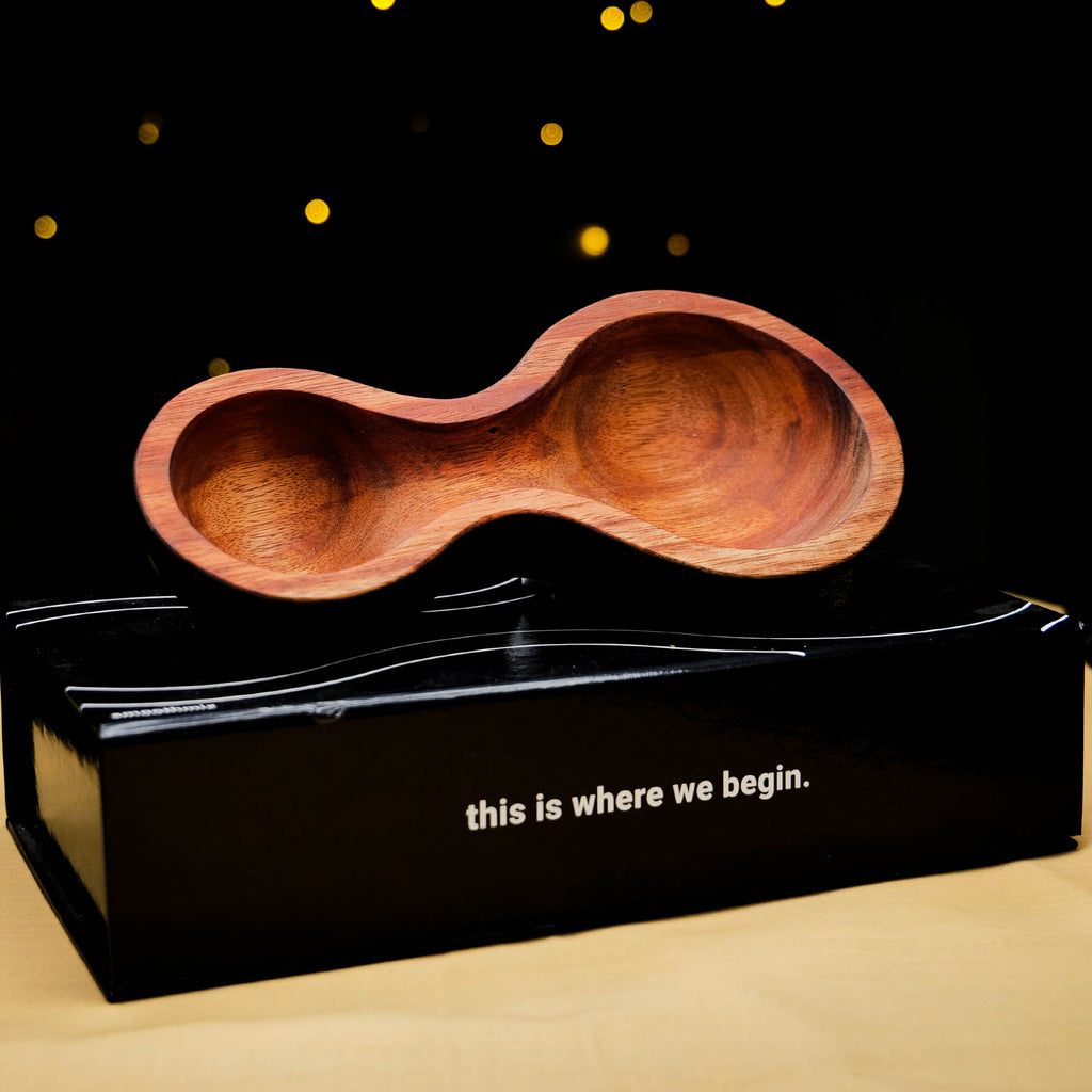 A handcrafted Smoothmix herbal mixing bowl with burnt edges, displayed on top of a black box with the text 'this is where we begin.'